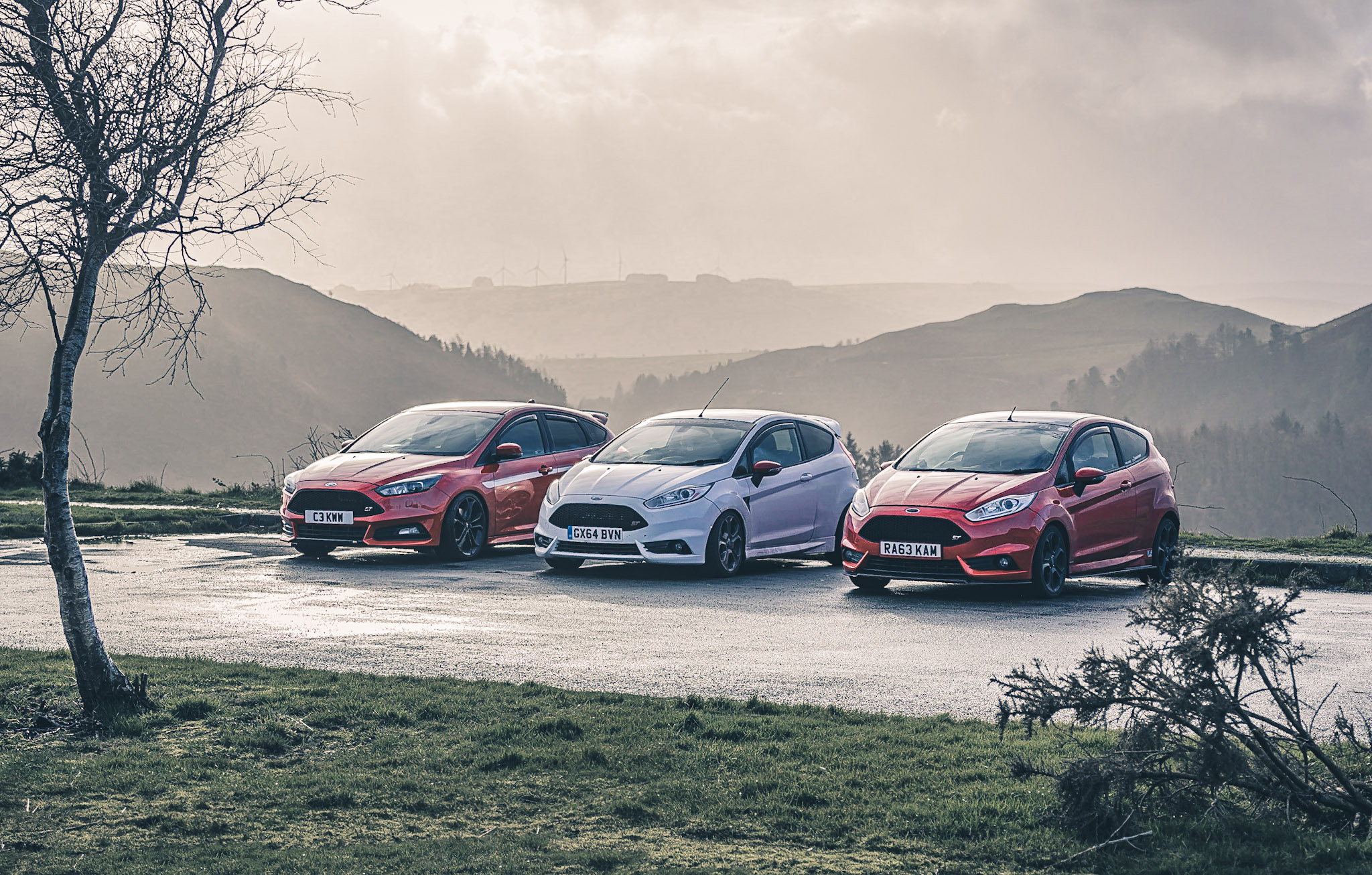 Group of cars parked on a hillside.